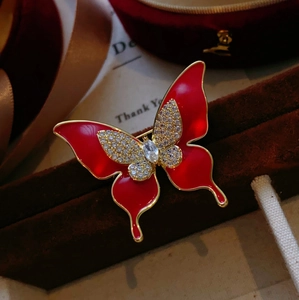 Broche papillon rouge élégante avec placage d'or et zircons sur fond de soie de luxe
