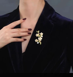 Detail of peach blossom brooch with pearls and ruby on a dark velvet blazer
