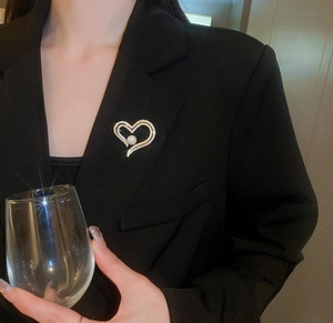 Detail of elegant gold heart brooch with pearl and crystals pinned on a black suit