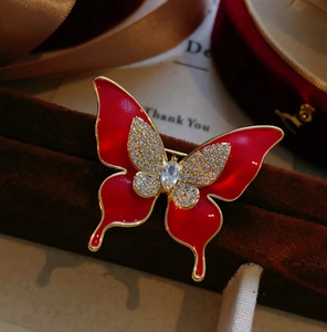 Détail macro d'une broche papillon en émail rouge avec cristaux brillants et alliage doré