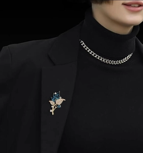Detail of elegant blue orchid leaf brooch with marquise gemstones on black suit lapel