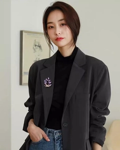 Detailed view of an elegant purple gemstone brooch in plant leaf shape on dark suit