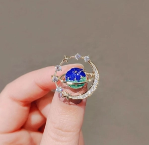 Macro shot of celestial earth brooch with crescent moon and stars in gold finish