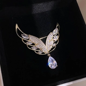 Detail der Engelsflügel-Brosche mit Goldbeschichtung und funkelndem Kristallanhänger