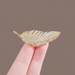 Elegante spilla a piuma dorata con micro-cristalli per decorazione di abiti e completi