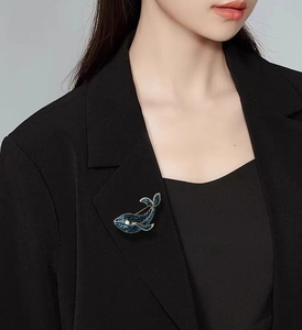 Broche baleine bleue avec bordure dorée et perle blanche sur un revers de costume