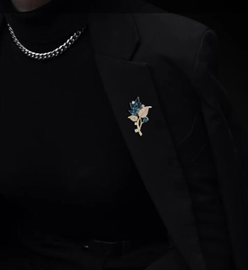 Detail view of an elegant orchid brooch with blue marquise crystals on black suit