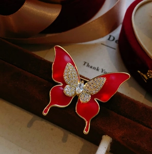 Détail de broche papillon en émail rouge avec cristaux étincelants sur métal doré
