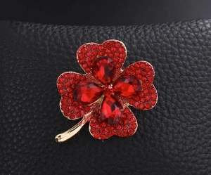Vue détaillée d'une broche trèfle à quatre feuilles avec cristaux rouges et or