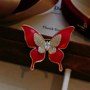 Vue macro détaillée d'une broche papillon rouge vintage avec cristaux et cadre doré