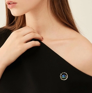 Detailed view of creative starry planet brooch with blue enamel and sparkling small stones