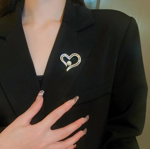 Detail of a gold heart brooch with pearls and zircons on a black suit lapel