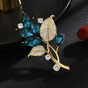 Elegant gold orchid brooch with deep blue stones and white zircon crystals on dark background