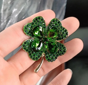 Vue macro d'une broche trèfle à quatre feuilles vert étincelant avec base dorée