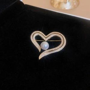 Detail shot of a heart pearl brooch with micro-pave crystals on black velvet