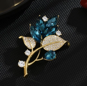 Elegant gold orchid brooch with deep blue crystals and white cubic zirconia accents