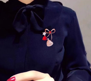 Dettaglio di elegante spilla a ciliegia con cuori e diamanti scintillanti su seta