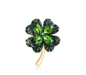 Détail macro de la broche trèfle à quatre feuilles dorée avec strass verts scintillants