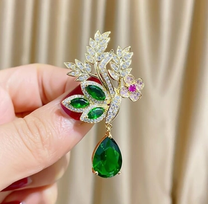 Détail de la broche épi dorée avec pierres vertes et pendentif cristal en goutte