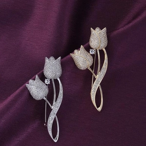 Détail de broches tulipes dorées et argentées avec cristaux sertis sur velours