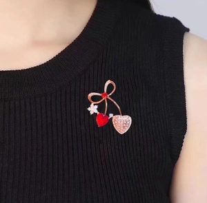 Dettaglio ravvicinato della spilla a cuore con cristallo rosso su abito nero elegante