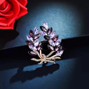 Elegant purple crystal wreath brooch in rose gold alloy set on a dark textured background