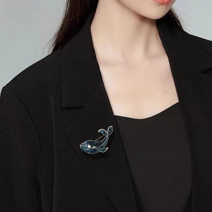 Broche baleine en cristal bleu scintillant dorée sur un revers de veste noir