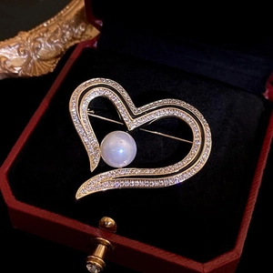 Close-up of heart-shaped pearl and zircon brooch in a premium red jewelry gift box