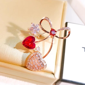 Elegante spilla a cuore in oro rosa con gemme rosse e dettagli floreali scintillanti