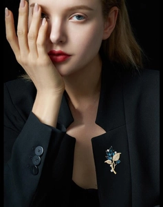 Detailed close-up of elegant orchid leaf brooch with blue crystals on a black blazer