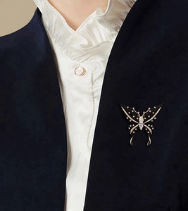 Detail of elegant black and gold butterfly brooch with crystals on a navy velvet suit lapel