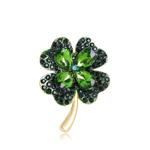 Élégante broche trèfle à quatre feuilles avec cristaux verts et base dorée sur fond blanc