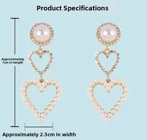 Detail of 925 silver needle drop earrings featuring heart pearls and rhinestones