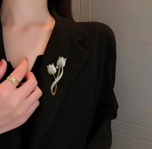 Gros plan d'une broche tulipe dorée avec zircons blancs sur une veste noire
