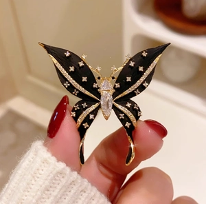 Detail of a luxury black butterfly brooch with gold edges and pavé crystal wings