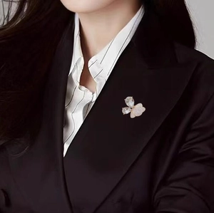 Broche papillon dorée élégante avec pierres en cristal sur une veste de costume noire