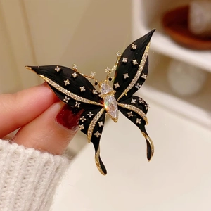 Elegant black and gold butterfly brooch with sparkling crystals on a matte wing design