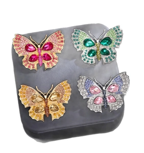 Vue détaillée de broches papillon en cristal aux multiples couleurs et finitions métalliques