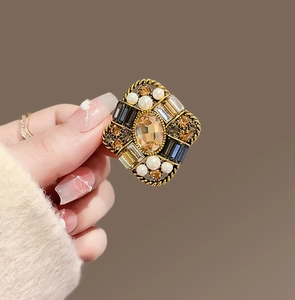 Close-up of vintage gold brooch with amber gemstone, pearls and rhinestones decoration