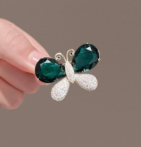 Nahaufnahme einer Vintage Schmetterlingsbrosche mit grünen Kristallen und glänzenden Strass