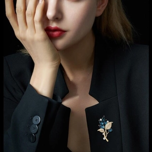 Elegant gold orchid brooch with deep blue marquise gems on a black suit jacket