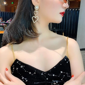 Close-up of heart-shaped pearl drop earrings featuring three tiers of elegant pearls