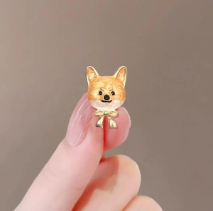 Gros plan d'une jolie broche Shiba Inu en émail avec un petit nœud doré détaillé