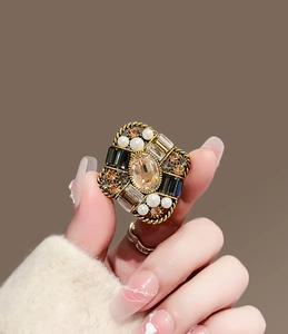 Detail view of vintage gold ring with amber stone, pearls and crystals on hand