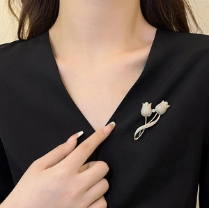 Vue détaillée d'une broche tulipe dorée ornée de strass brillants sur un vêtement noir