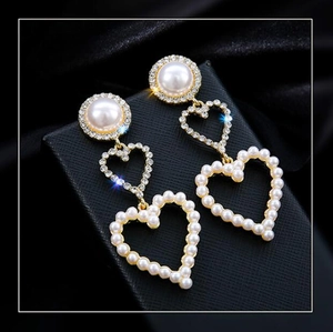 Macro shot of 925 silver long bridal earrings with heart pearls and sparkly rhinestones