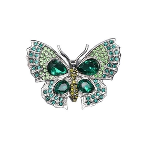 Détail d'une broche papillon argentée ornée de cristaux dégradés émeraude et jaune