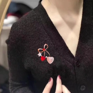 Spilla fiocco oro rosa con pietra a cuore rosso e dettagli floreali su maglia nera