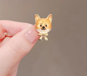 Gros plan de la mignonne broche Shiba Inu en émail avec nœud papillon doré sur fond sobre