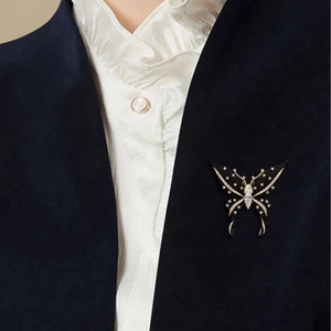 Exquisite black and gold butterfly brooch with white crystals pinned to a navy blazer lapel